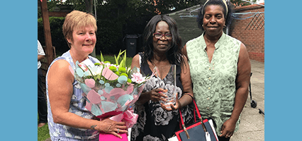 Inez receiving a commemorative glass and flowers from her current manager, Dorinda along with her former manager